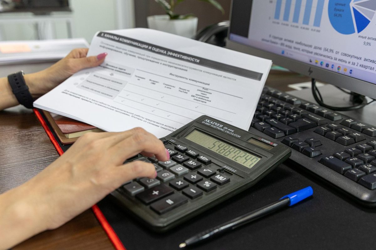 Hands using a calculator next to a printed financial document on a desk