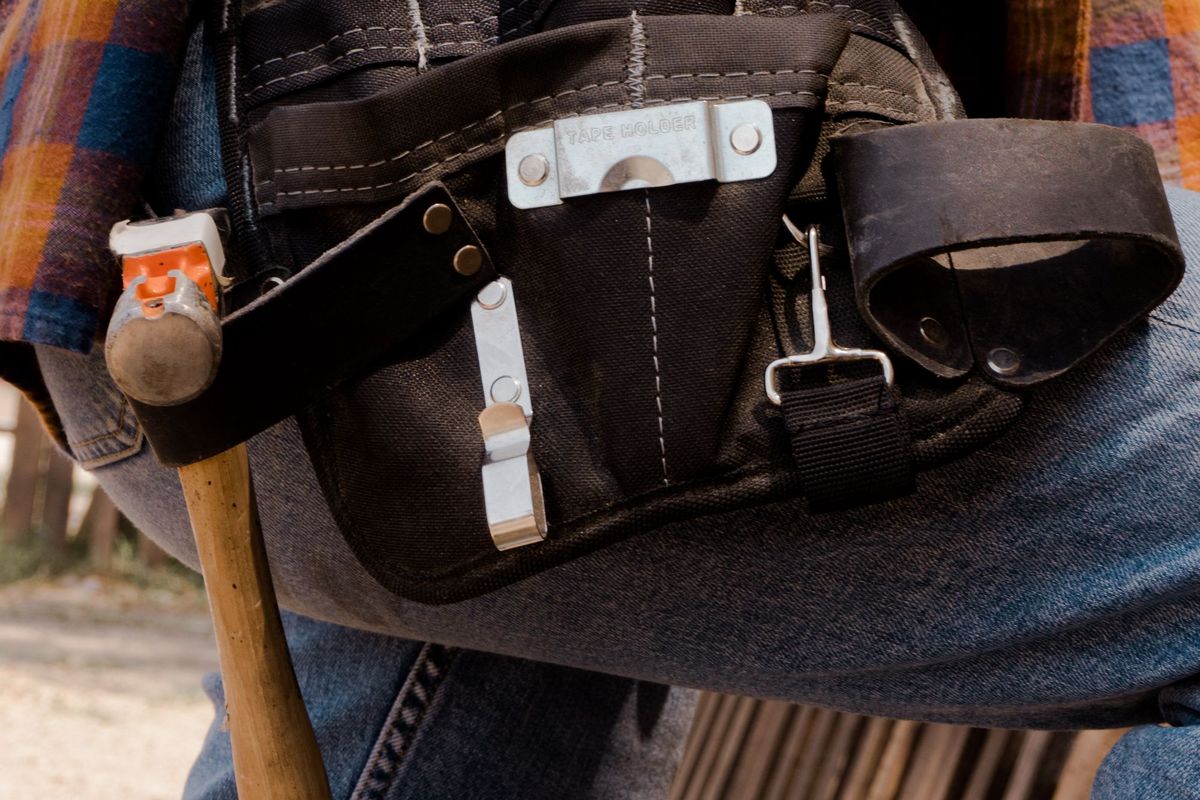 A tool belt with a hammer, worn by a worker in jeans