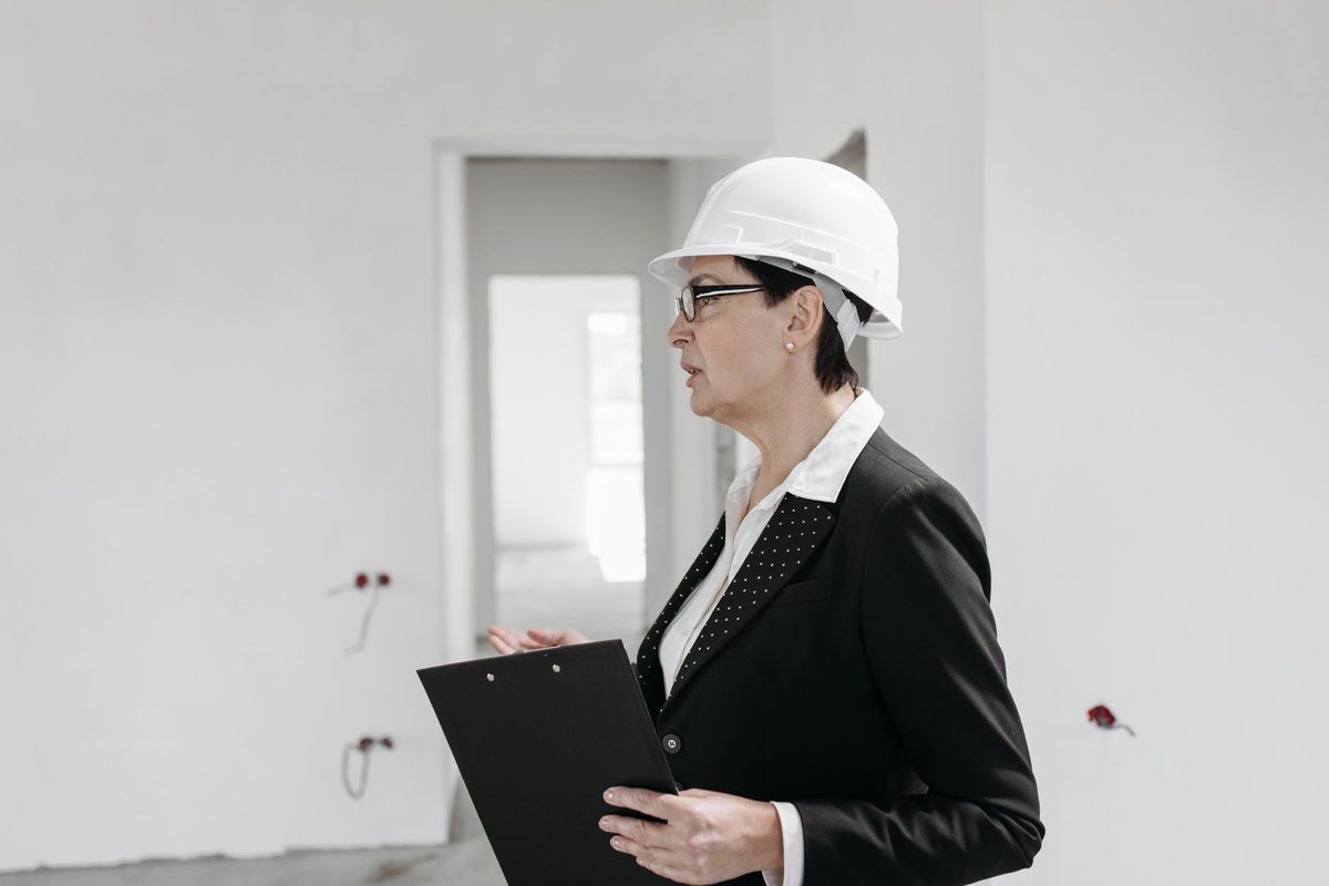 Inspector in a white hard hat holding a clipboard in an unfinished room