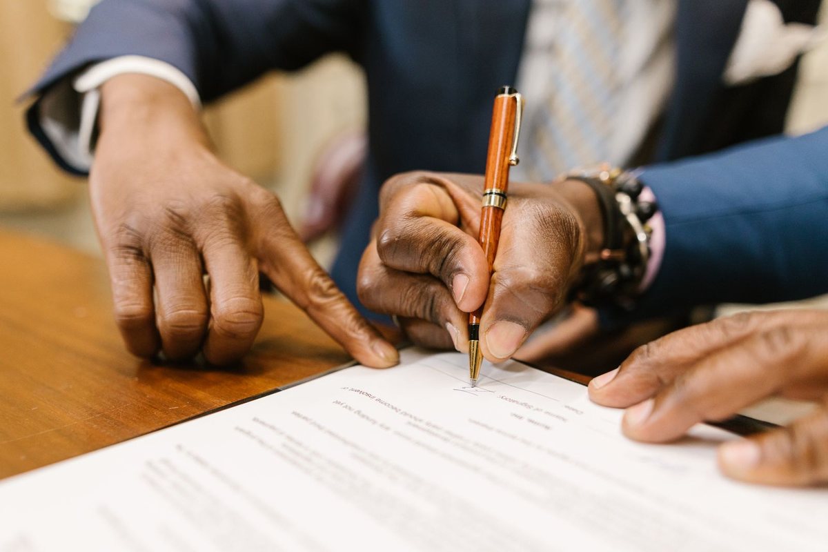 Person signing a written contract with a pen