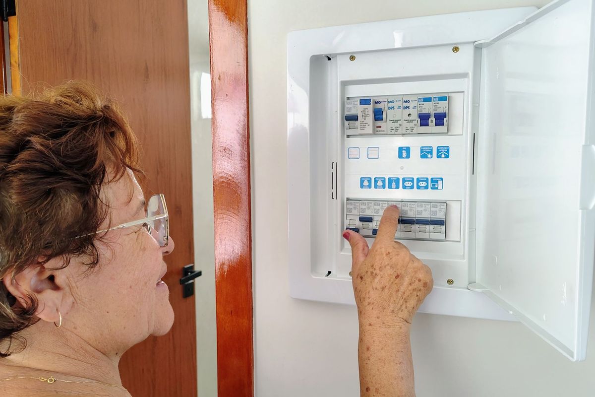 A woman switching a breaker in a home electrical panel