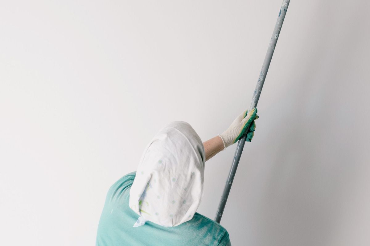 A person painting a ceiling with a roller on an extension pole
