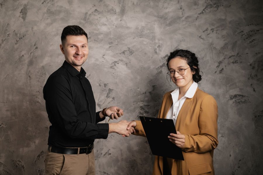Two people shaking hands, one holding a clipboard