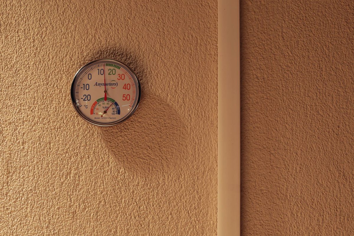 Round temperature and humidity gauge mounted on a textured wall