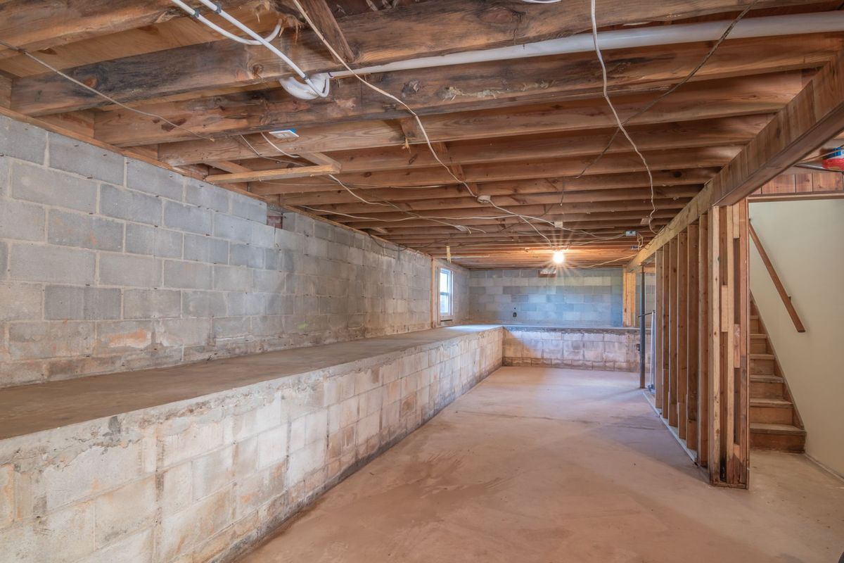 Empty, unfinished space with block walls and open ceiling joists