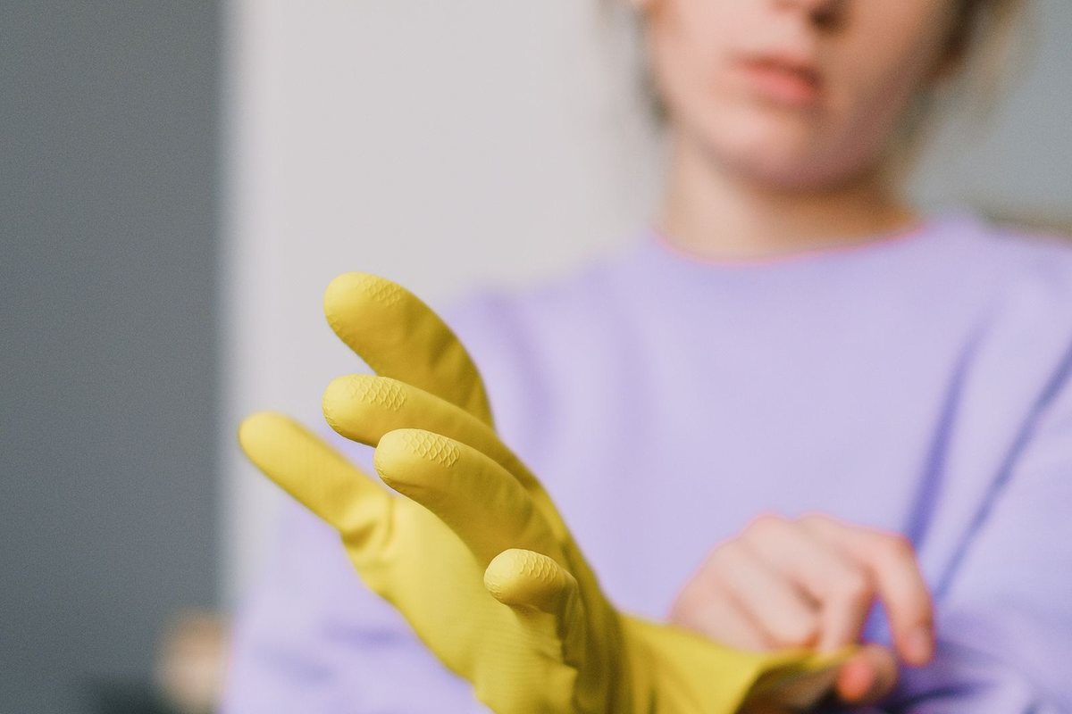 Person pulling on yellow rubber cleaning gloves