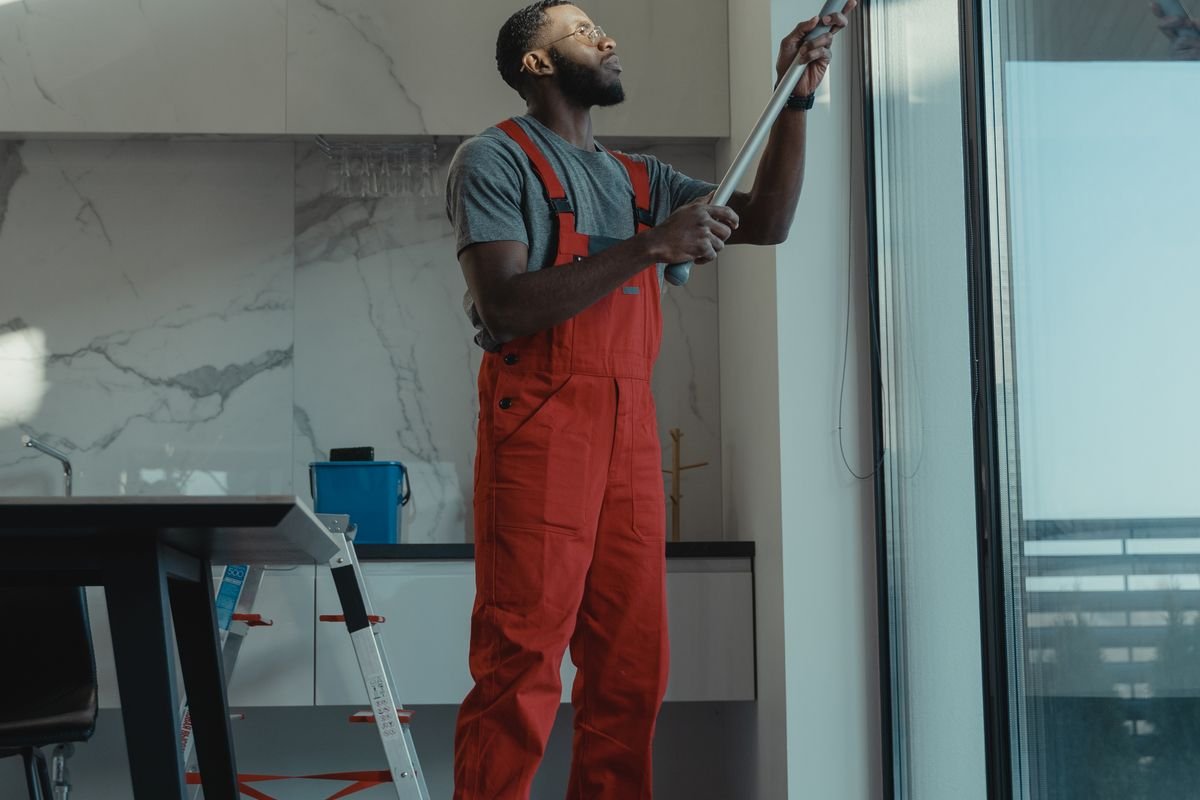 Man cleaning a tall window and its frame with a pole