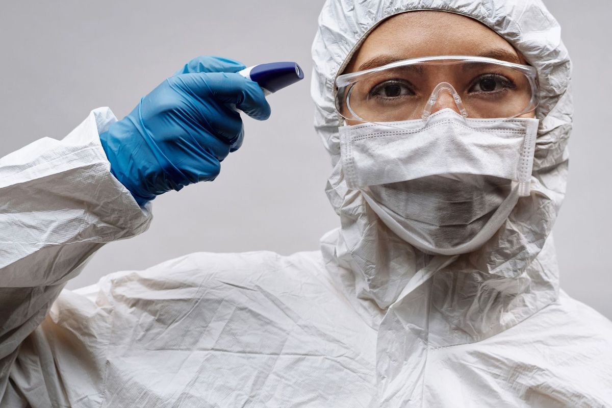 Person wearing a protective suit, goggles, respirator and gloves
