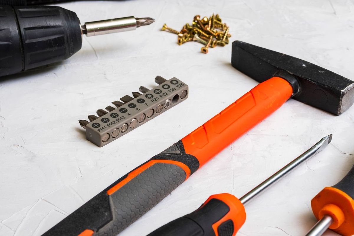 Hammer, drill and screwdriver laid out on a white surface