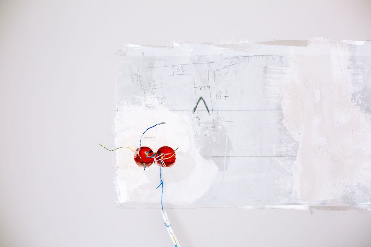 Exposed electrical wiring in an unfinished white wall