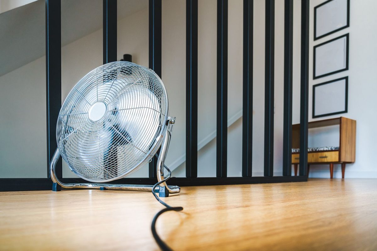 A metal floor fan on a light wood floor