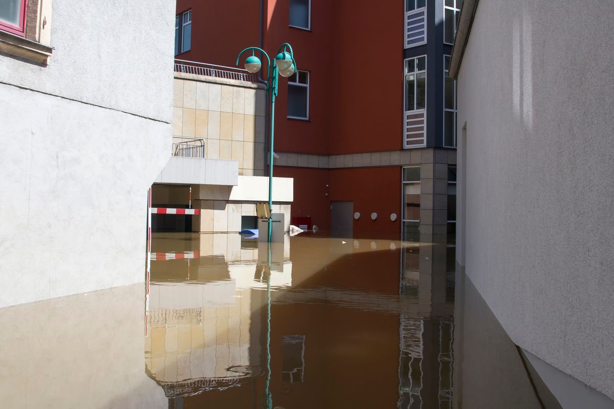 Floodwater standing between buildings, with the water line showing on the walls