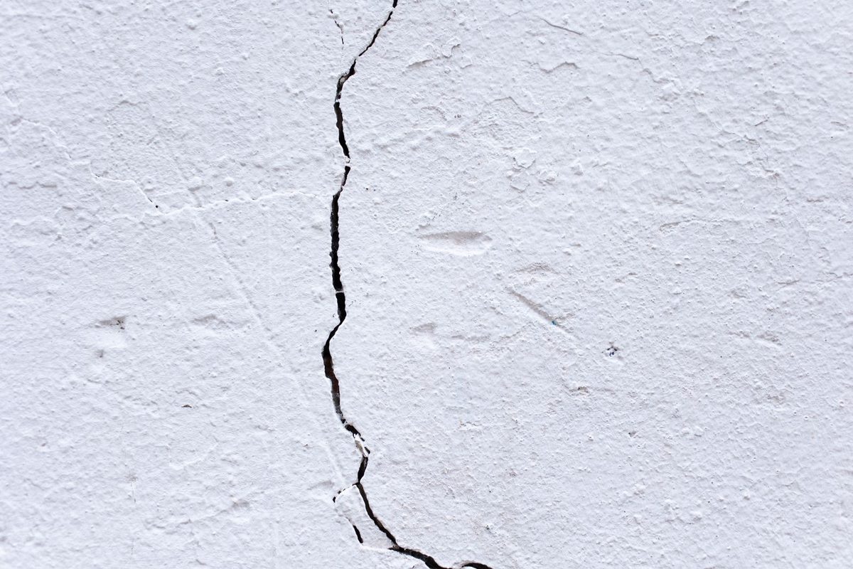A long crack running down a white plaster wall