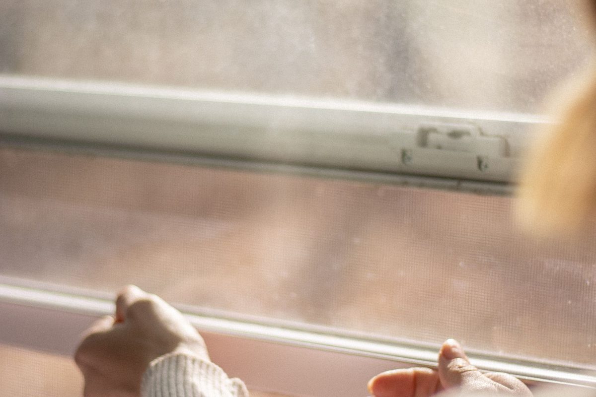 Close-up of a hand on the frame of a window, checking the sash