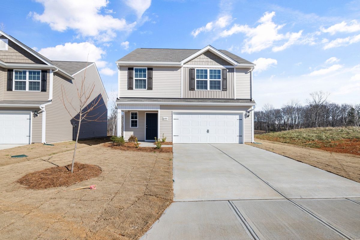 A two-story house with a white garage door and a concrete driveway