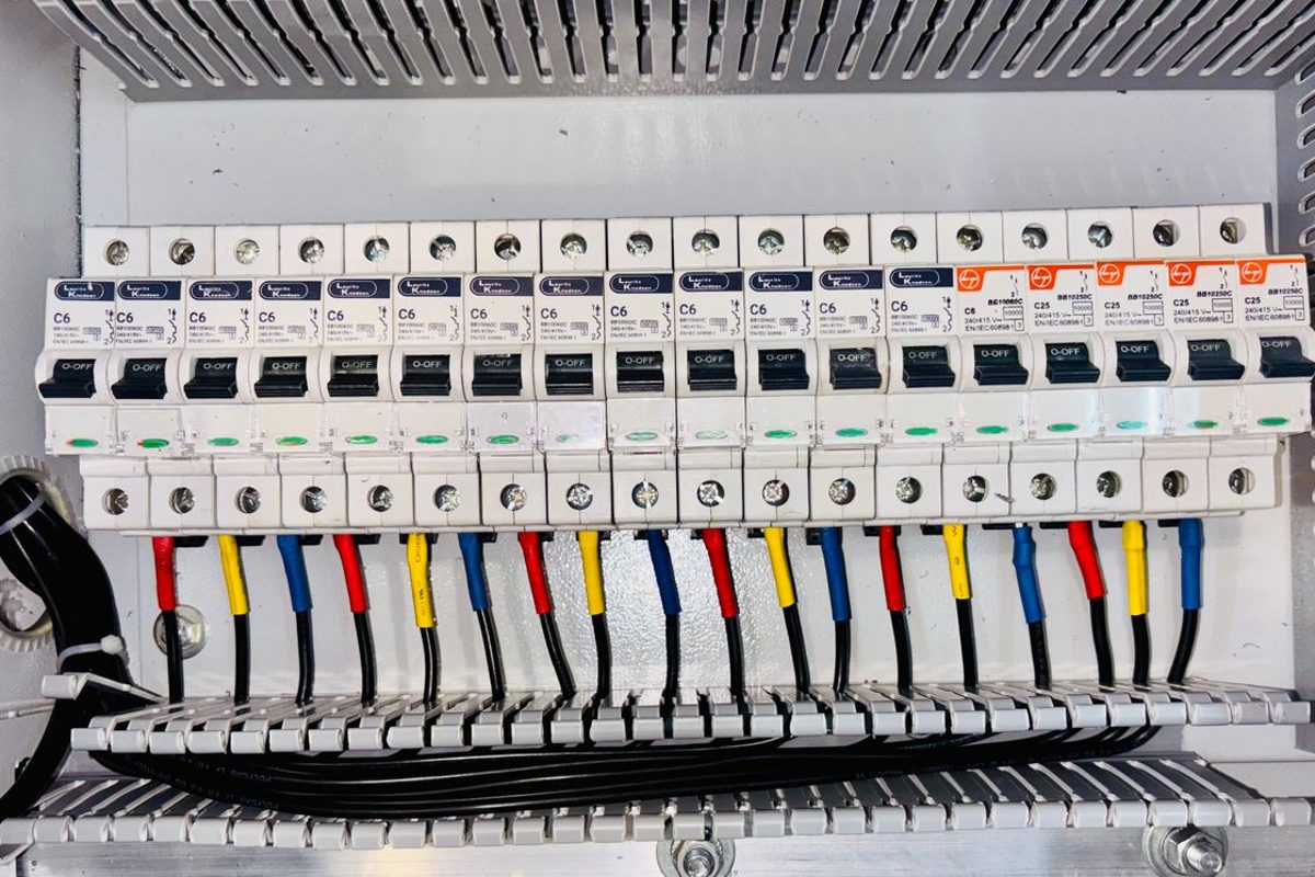 A residential-style circuit breaker panel with rows of breakers and color-coded wires