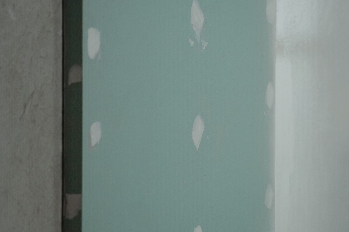 Close-up of new gypsum board on a wall with joint compound over the screws, ready for finishing