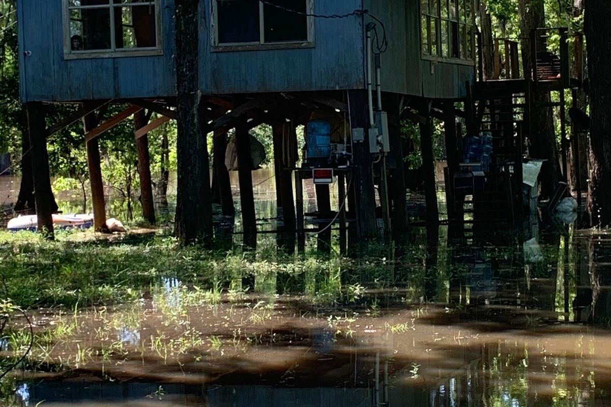Wooden house raised high on posts with floodwater underneath